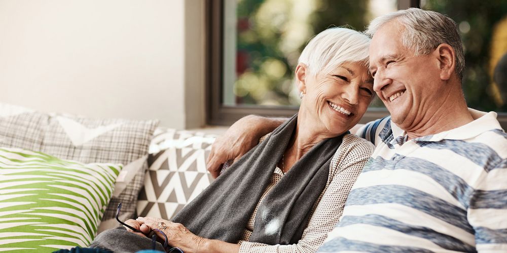 Älteres Ehepaar sitzt lächelnd auf einem Sofa
